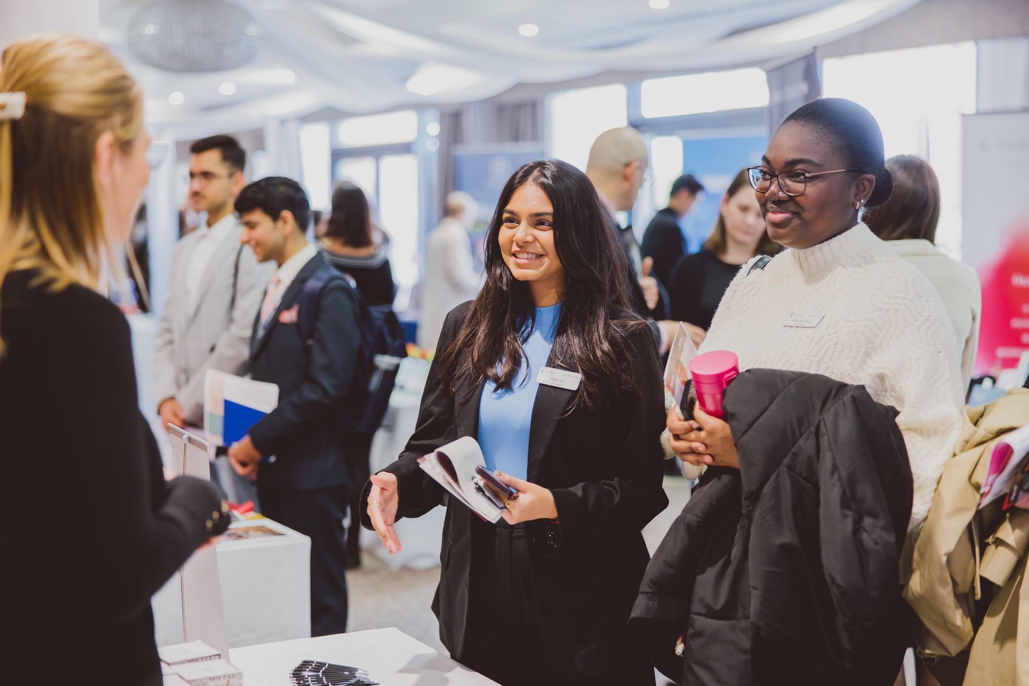 Two young hospitality professionals engage with a stand holder at a conference