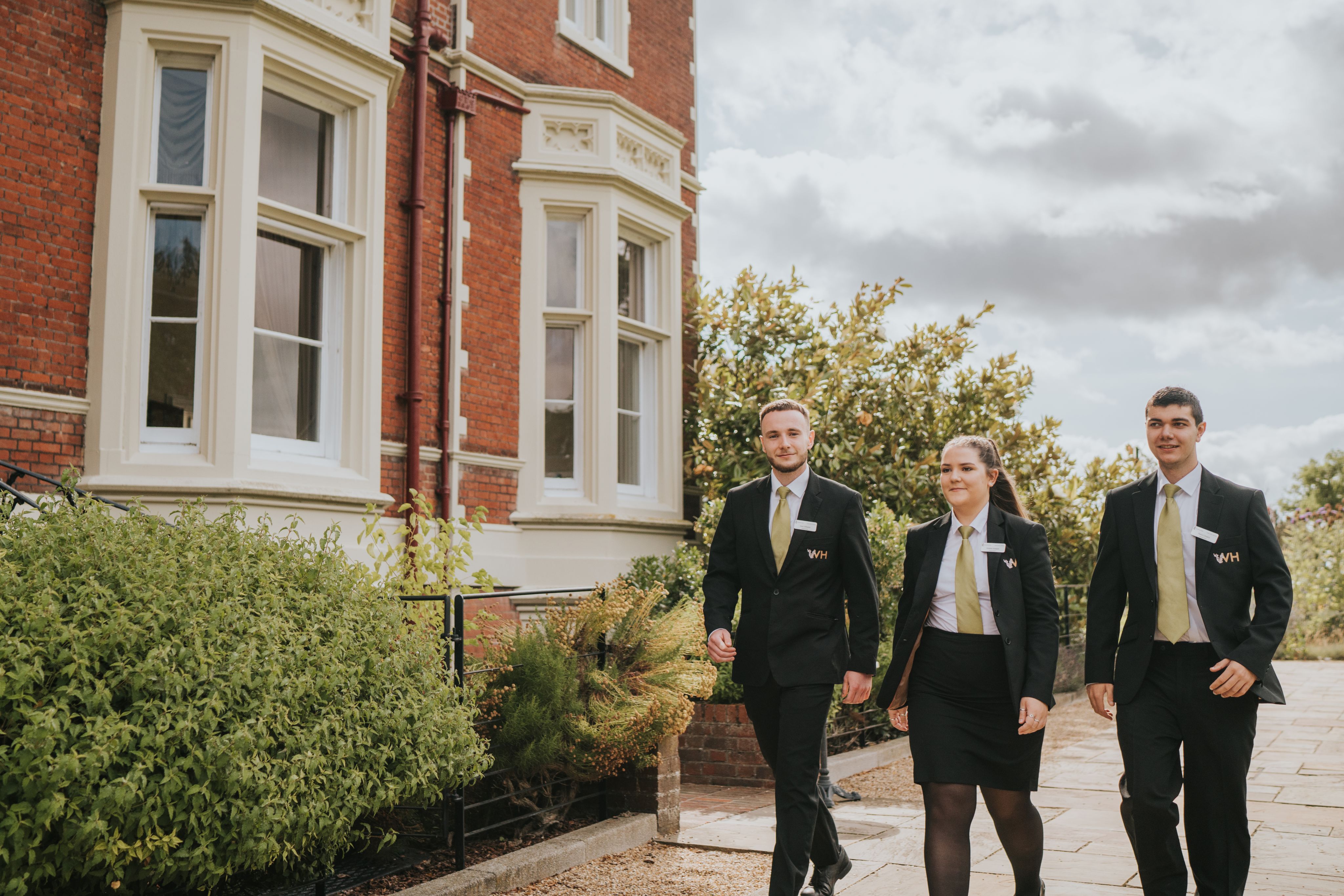 Three young hospitality professionals walking outside Wivenhoe House Hotel