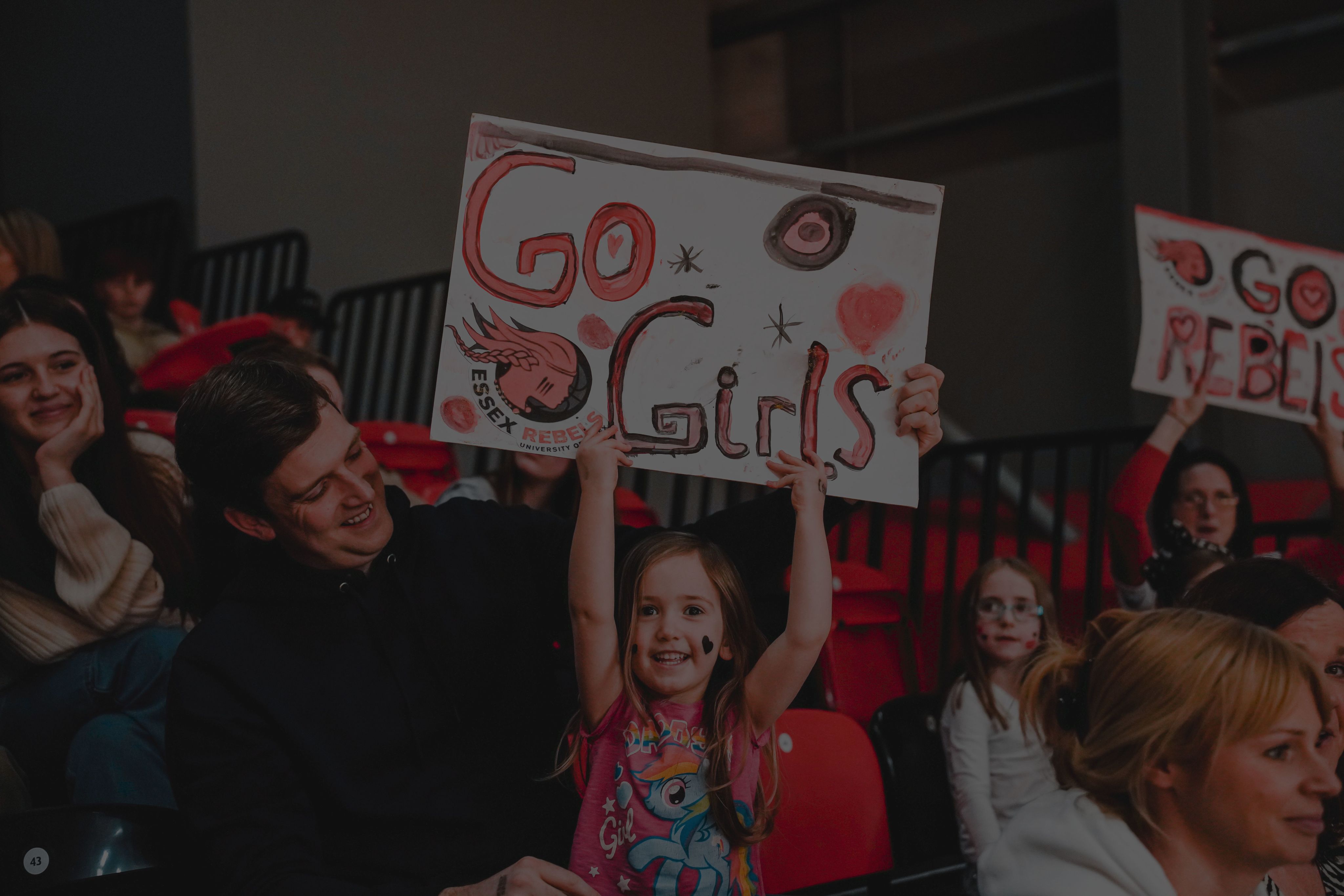 A young Essex Rebels fan holding a 'Go girls' banner.