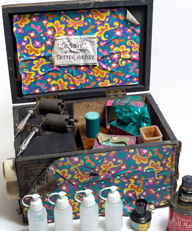 A small wooden box colourfully painted and filled with bottles and pieces of tattooing equipment, from the Jessie Knight collection, courtesy of the Museum of Wales