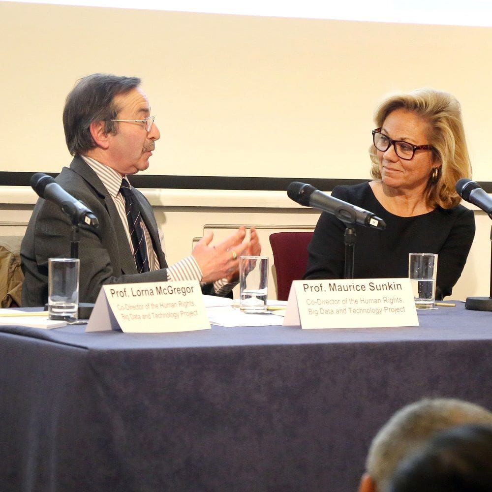 Human rights academics discussing in front of a microphone