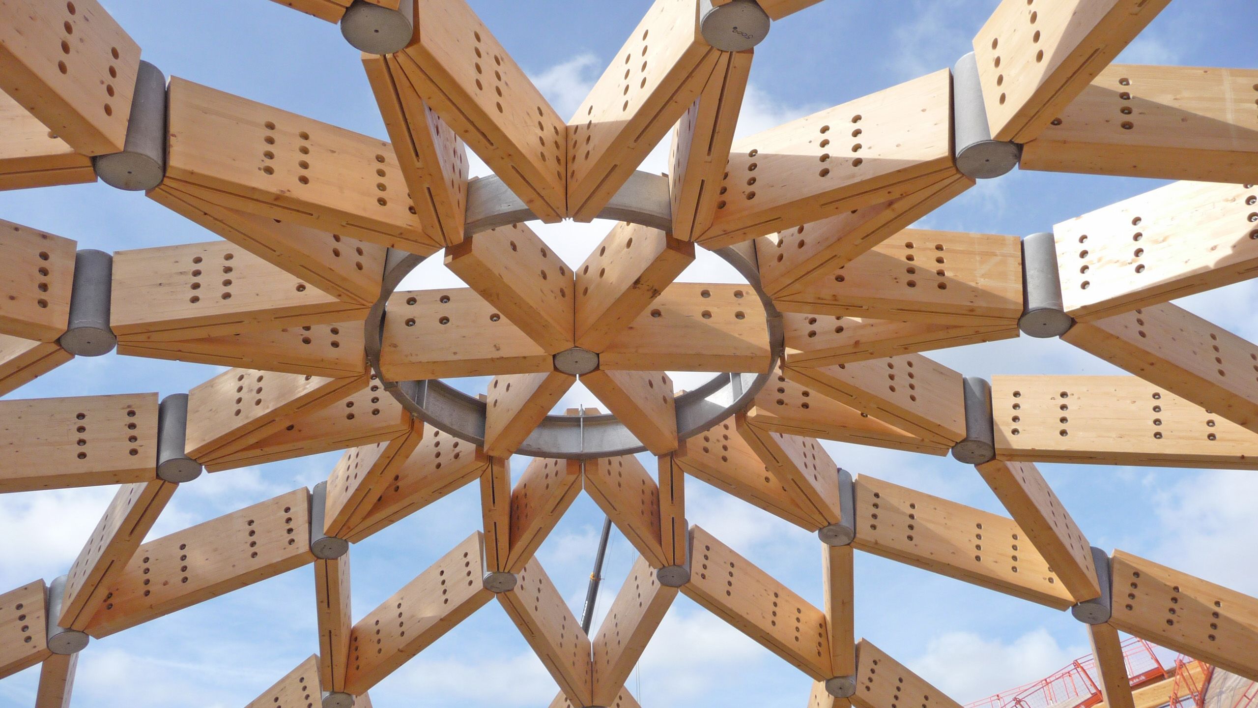 The roof timbers of Essex Business School's main lecture theatre form a star shape. The partially-constructed roof remains open to a blue sky.