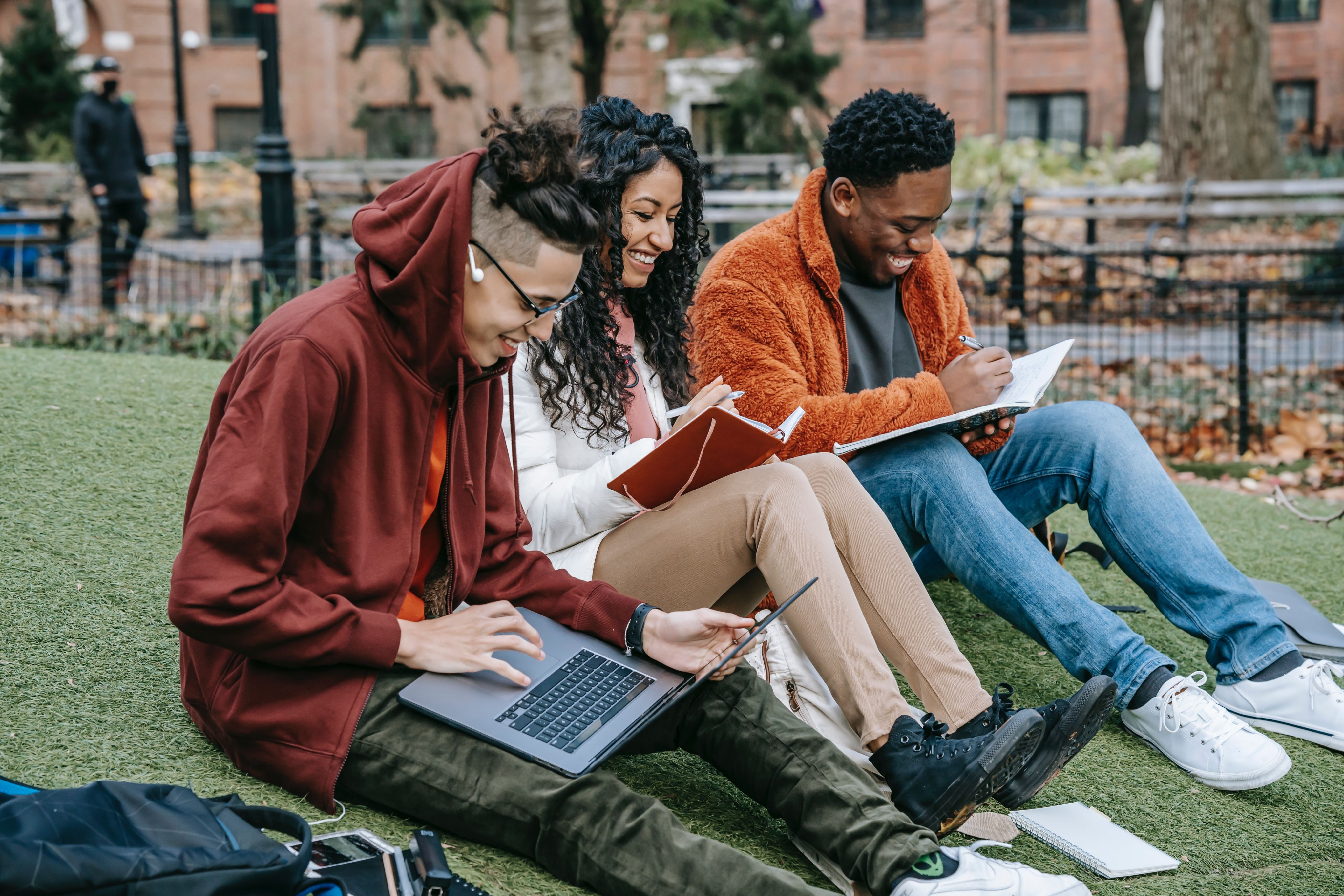 Students sitting outside looking at laptops